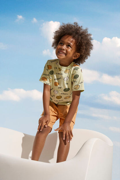 Kind trägt die Minymo Shorts in Orange – perfektes Sommeroutfit für Strand und Alltag.
