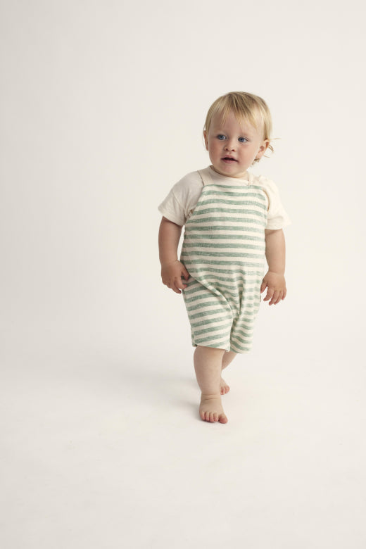 Kind trägt den Unisex Baby Overall 'Leo' in Grün mit feinen Streifen. Hergestellt aus biologischem Crepe-Stoff, leicht und bequem für den Sommer.