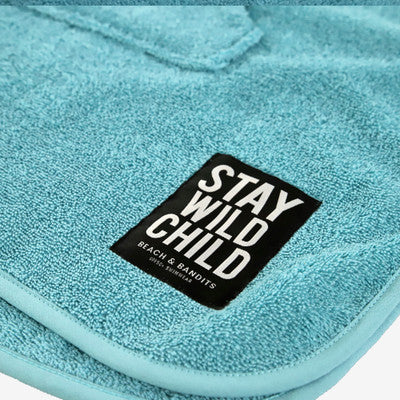 Detailansicht des "Stay Wild Child"-Patches auf dem Beach & Bandits Poncho Coastal in Türkis aus 100% Baumwolle.