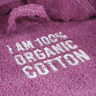 Detailansicht des Schriftzugs "I am 100% Organic Cotton" auf dem Beach & Bandits Poncho Orchid in Lila.