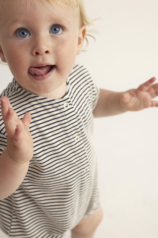 Fröhliches Baby im Unisex Strampler 'Luc' von Cozmo. Aus biologischem Frottee-Material mit stilvollem Streifen-Design.