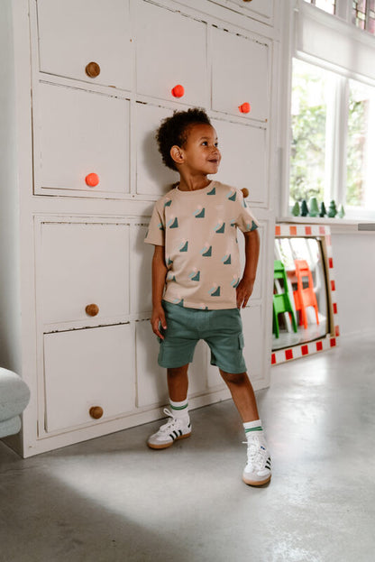 Kind trägt die Cargo Shorts in Ocean Green von Daily Seven, kombiniert mit einem Oberteil, Indoor-Szene.